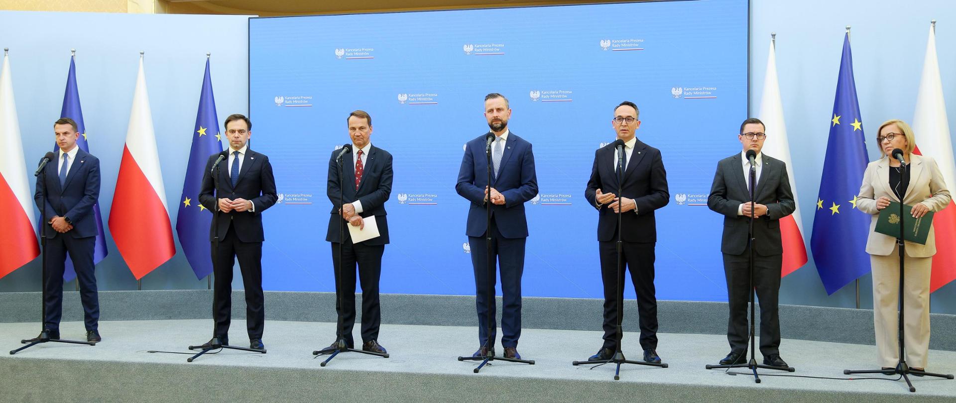 Wicepremier, Minister Obrony Narodowej Władysław Kosiniak-Kamysz, Ministra Klimatu i Środowiska Paulina Hennig-Kloska, Minister Energii Miłosz Motyka, Minister Finansów i Gospodarki Andrzej Domański, Minister Infrastruktury Dariusz Klimczak, Minister Spraw Zagranicznych Radosław Sikorski, Rzecznik rządu Adam Szłapka podczas konferencji 27.08.2025 r. W tle ekran z logo KPRM oraz flagi Polski i Unii Europejskiej.