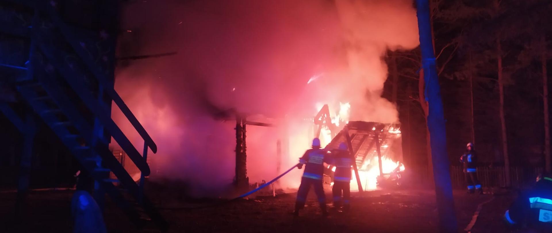 Strażacy gaszący palący się budynek.