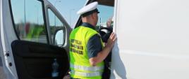 Umundurowany inspektor kujawsko-pomorskiej Inspekcji Transportu Drogowego pobiera wymagane dokumenty od kierowcy węgierskiego samochodu dostawczego.
