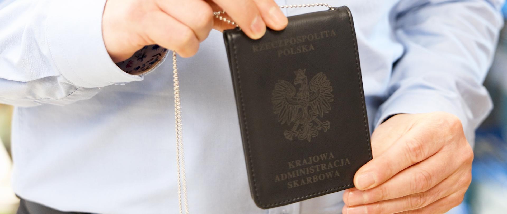 Osoba trzyma w dłoniach legitymację służbową Krajowej Administracji Skarbowej