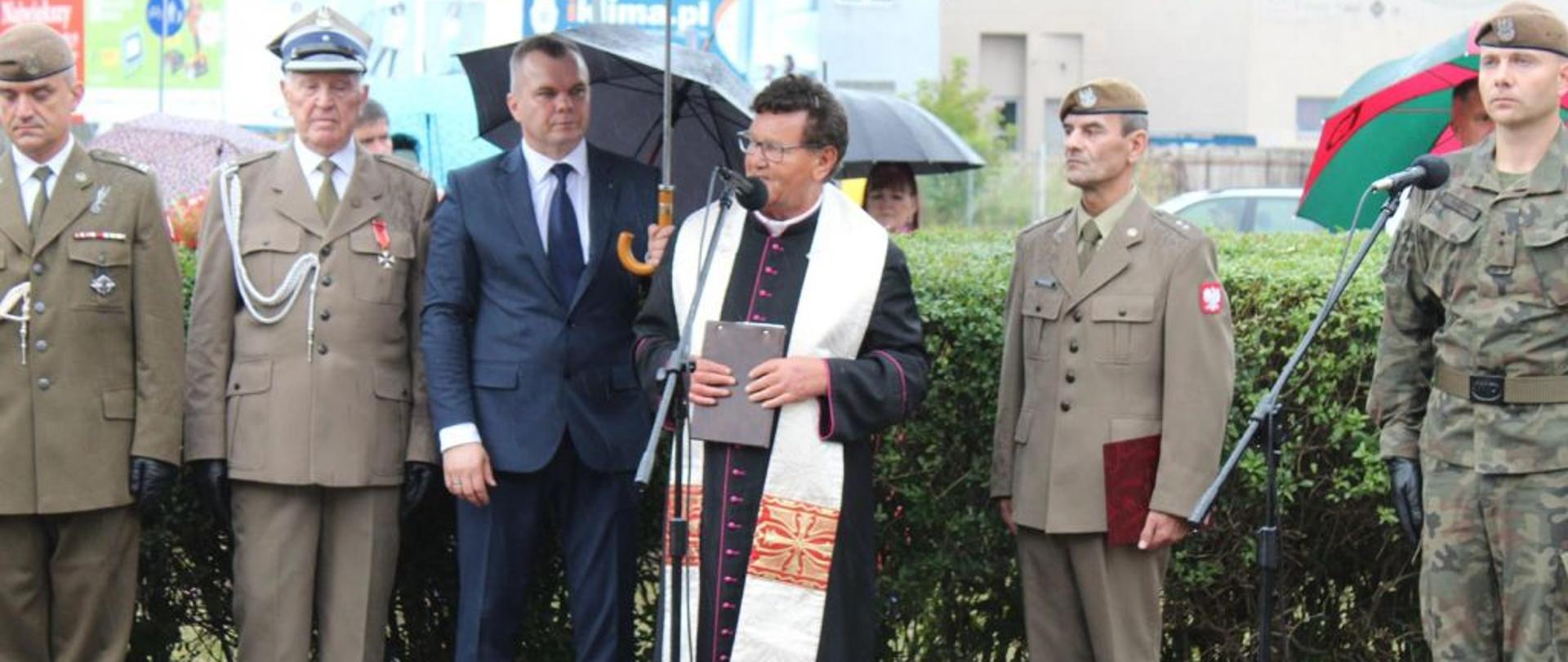 Na zdjęciu widoczni są żołnierze i ksiądz.