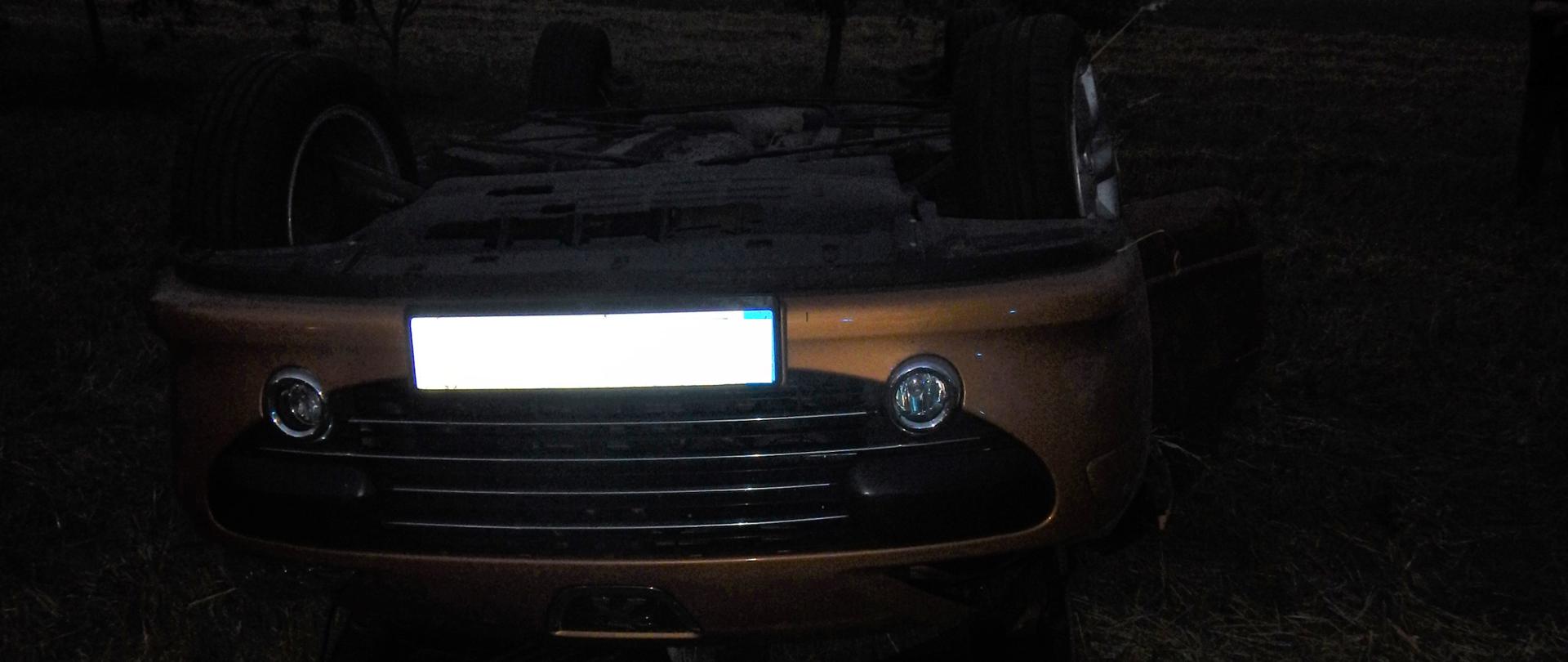 Zdjęcie przedstawia samochód osobowy po dachowaniu. Samochód leży na dachu.