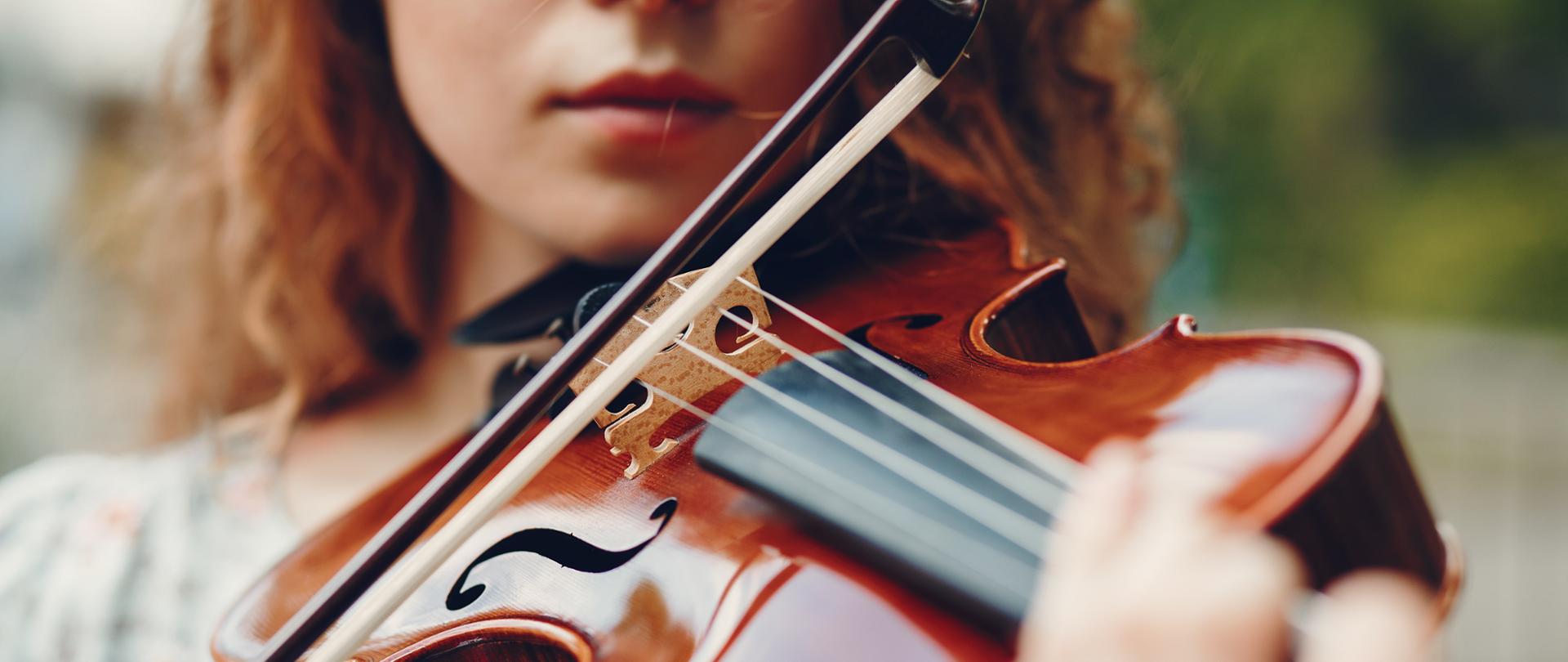 dziewczyna w parku grająca na altówce w letniej sukience