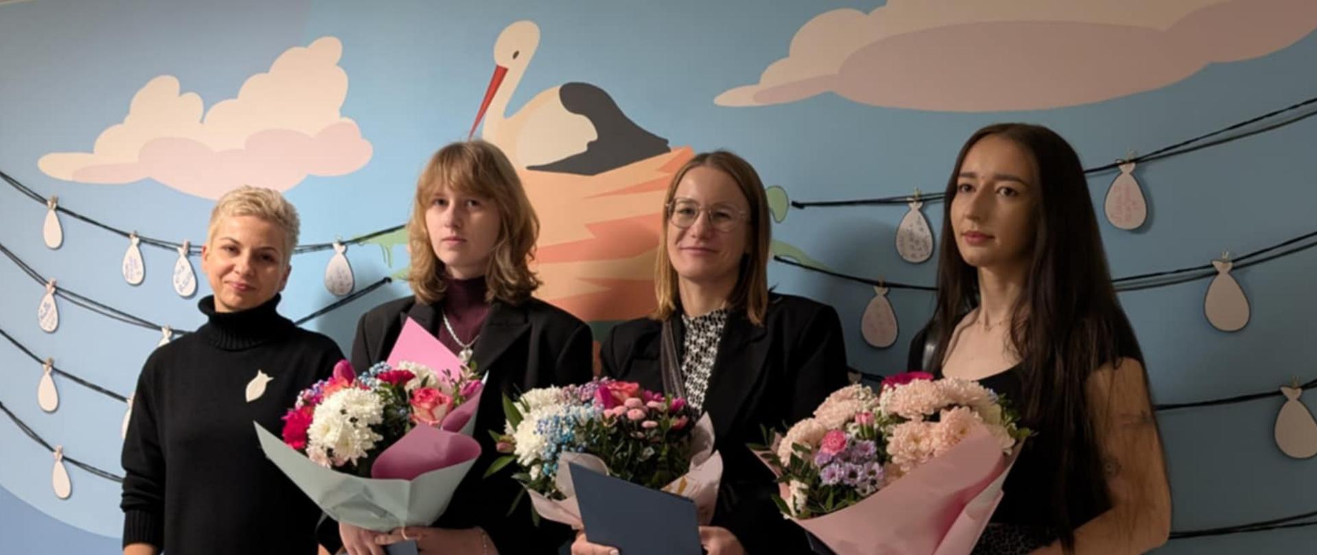 Grupa osób zaangażowanych w projekt z kwiatami i dyplomami.