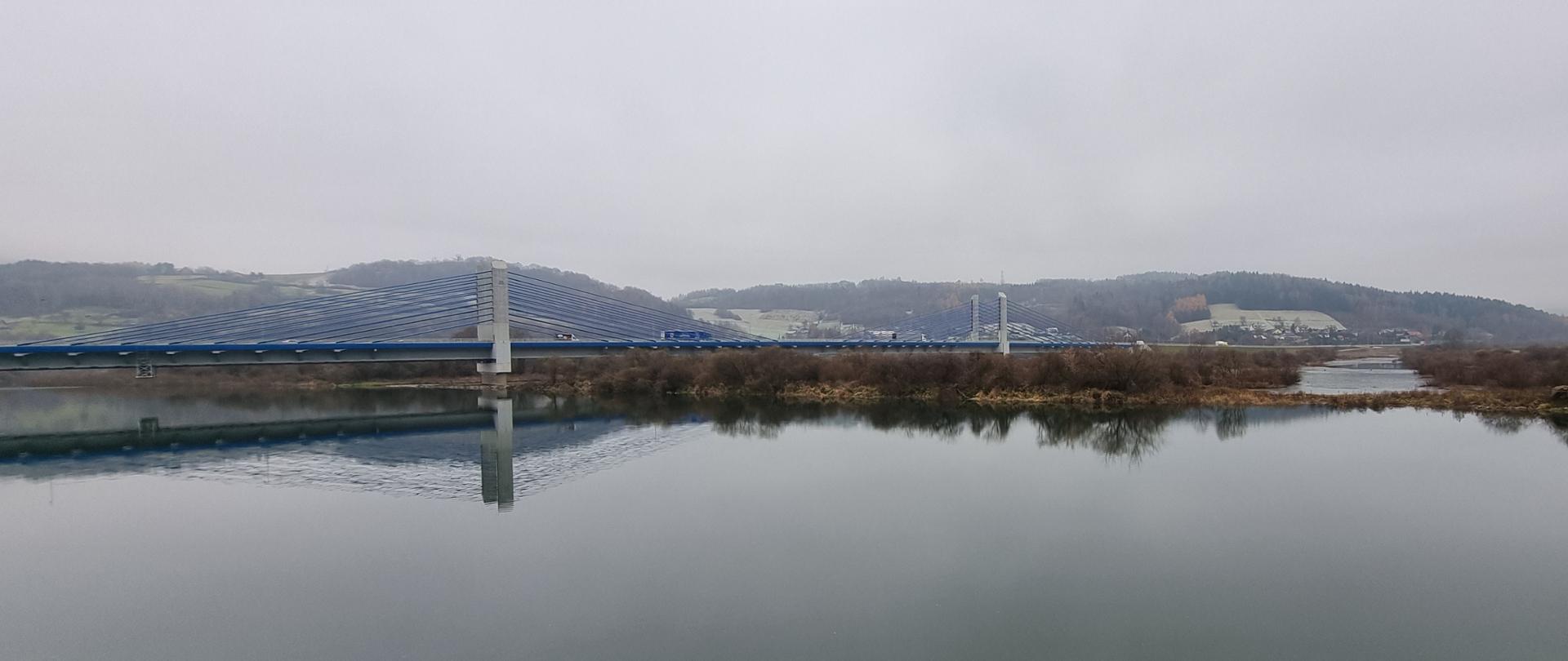 Długi most nad szeroką w tym miejscu rzeką Dunajec, w listopadowej szarości
