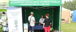 Zdjęcie przedstawia namiot Wojewódzkiego Inspektoratu Ochrony Roślin i Nasiennictwa w Lublinie oraz rolap. Inspektor wyjaśnia dwójce osób zadania Inspekcji.