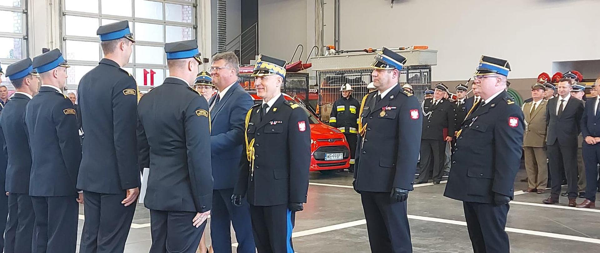 Po prawo w-ce minister Wąsik oraz komendant główny PSP, z-ca mazowieckiego komendanta wojeówdzkiego i komendant powiatowy podczas wręczania odznaczeń, po lewo strażacy PSP i OSP