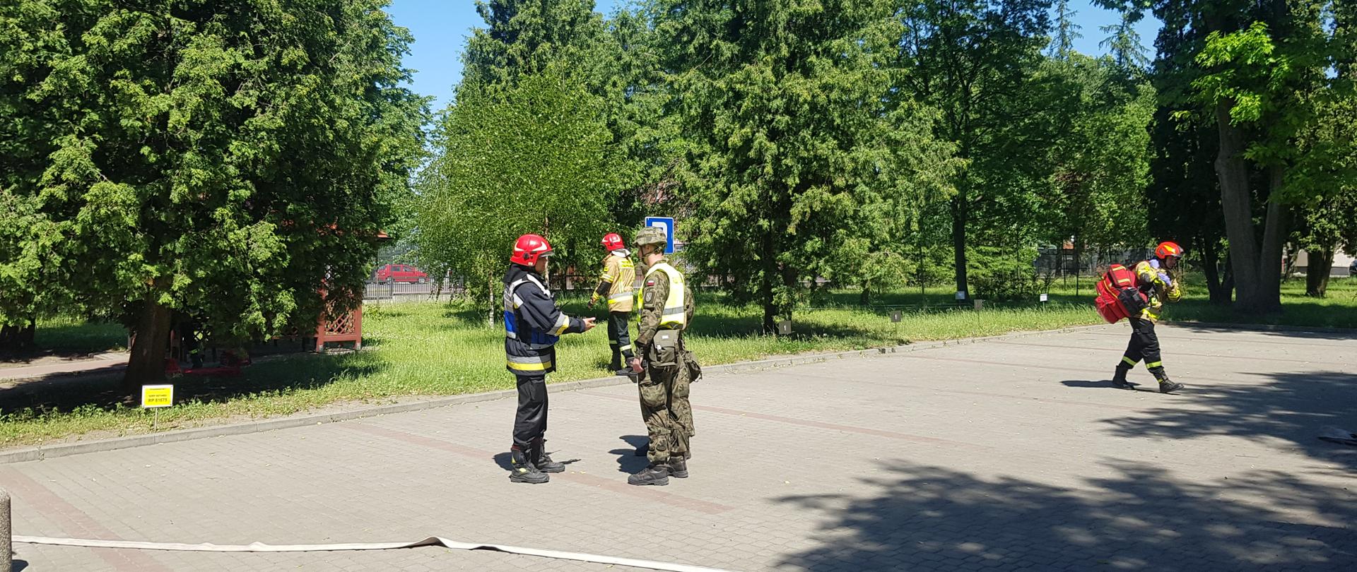 Kierujący działaniami ratowniczymi z Jednostki Ratowniczo Gaśniczej z Łomży pozyskuje informacje niezbędne na temat budynku do prowadzenia działań ratowniczo - gaśniczych od żołnierza.