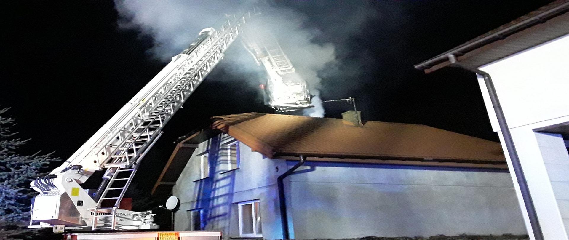 zdjęcie przedstawia pożar sadzy w kominie w budynku mieszkalnym jednorodzinnym, na pierwszym planie znajduje się podnośnik hydrauliczny strażacki 