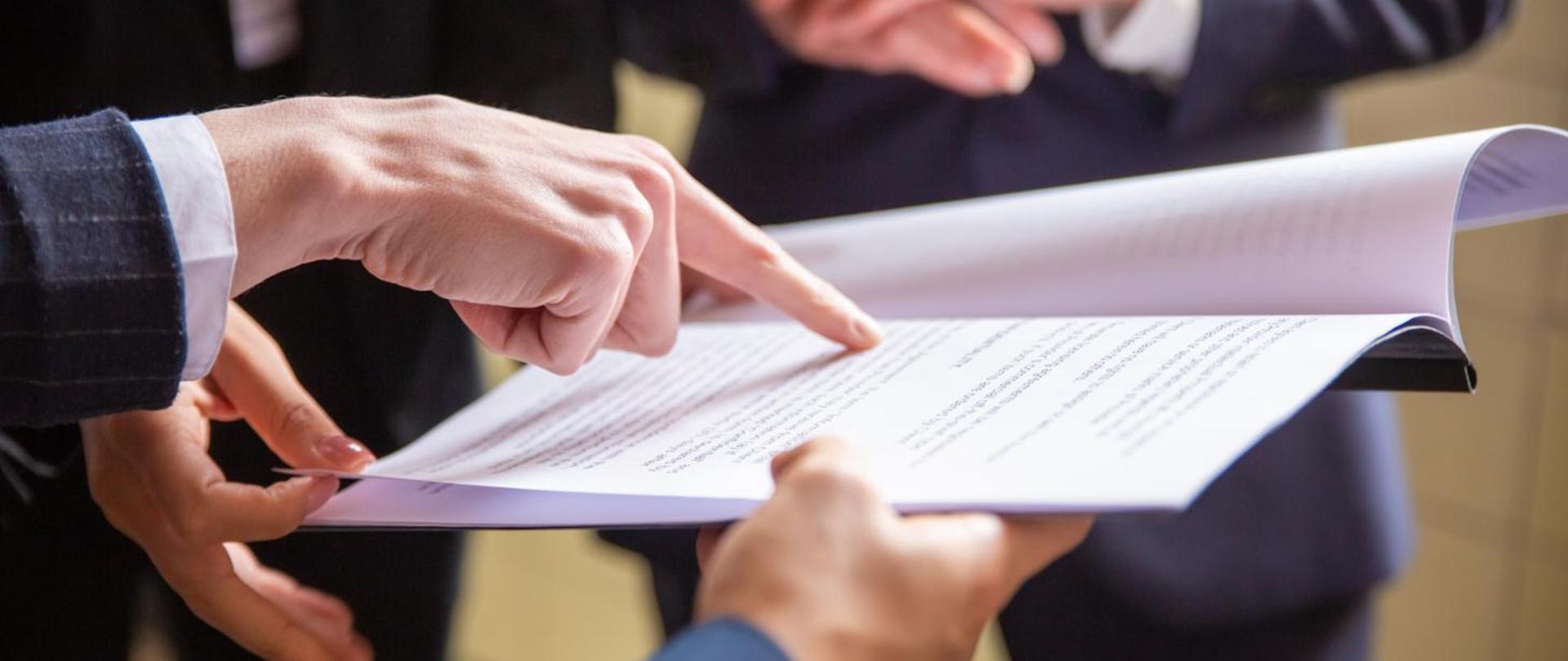 zdjęcie przedstawia palec wskazujący, który wskazuje jakiś tekst zapisany na kartce 