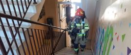 Widoczny strażak w pełnym umundurowaniu idący po schodach ośrodka