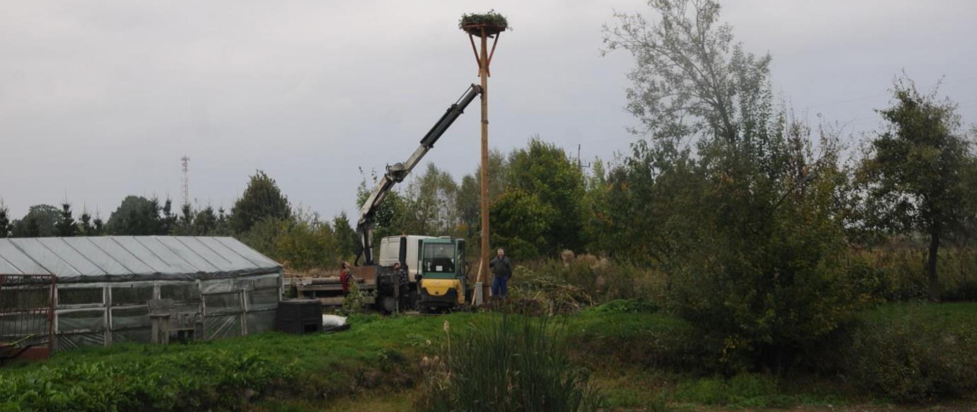 Prace związane z montażem słupa wolno stojącego i platformy pod gniazdo bociana białego w miejscowości Babiak, gmina Lidzbark Warmiński