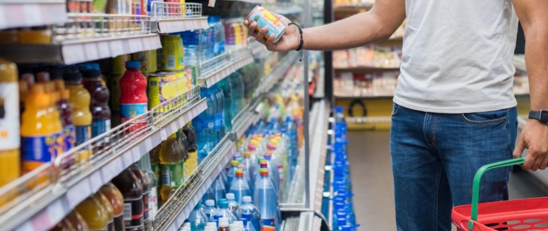 Mężczyzna wybiera w sklepie napój w puszce 