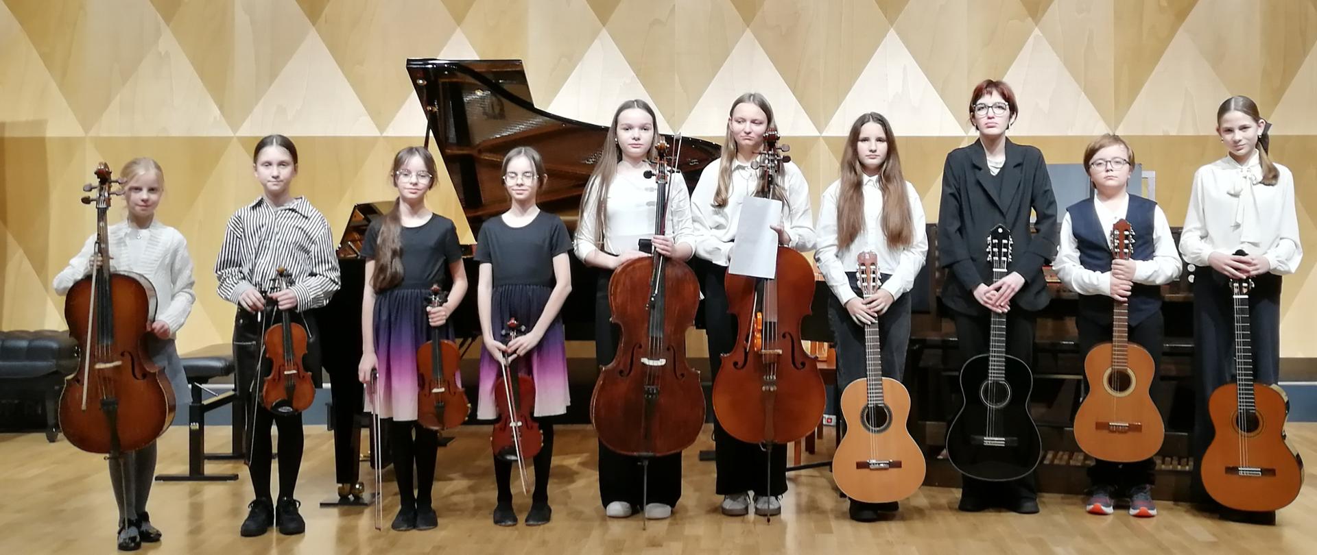 Grupa gitarzystów, skrzypków i wiolonczelistów na scenie sali koncertowej PSM