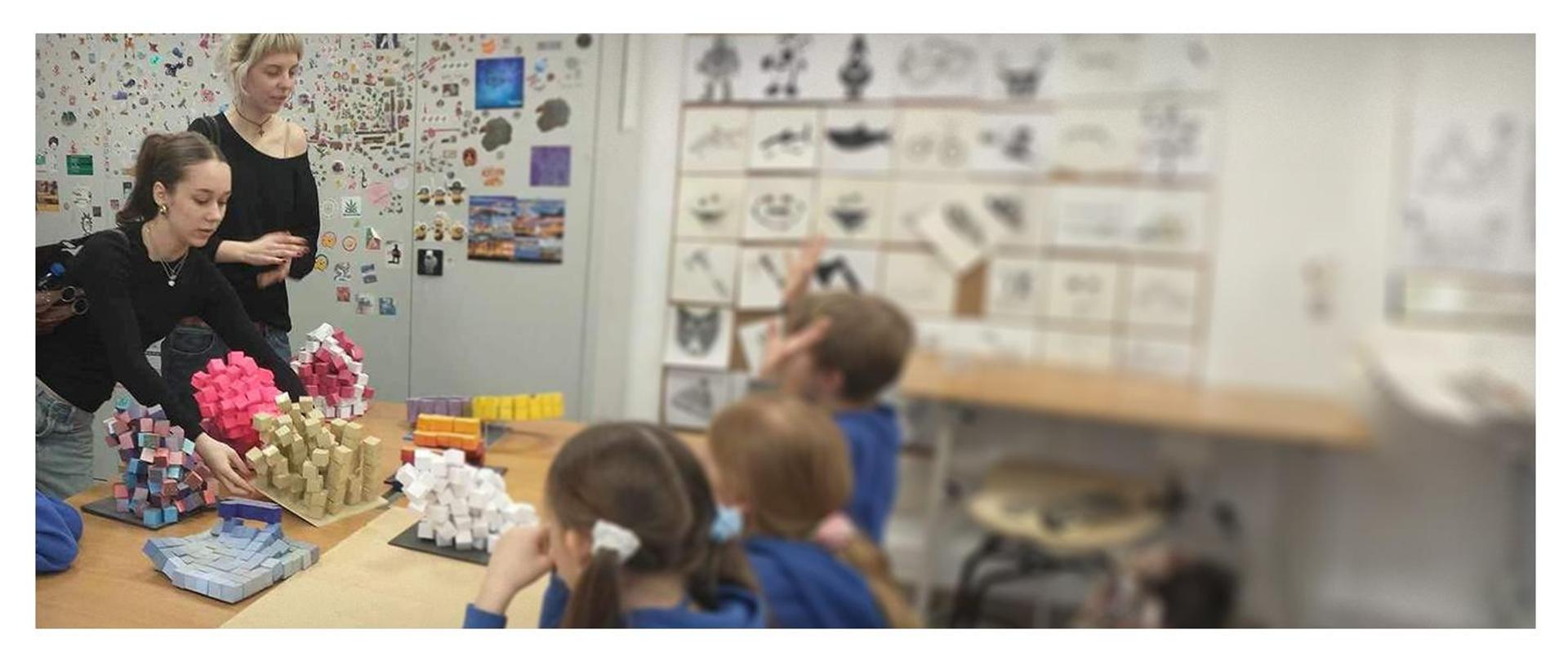 uczniowie oglądający kompozycje przestrzenne w sali szkolnej