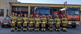 Na zdjęciu strażacy z JRG Wołomin w umundurowaniu bojowym na tle garażu w Komendzie Powiatowej oraz samochodów strażackich ustawieni w szyku podczas minuty ciszy za poległych w Ukrainie strażaków