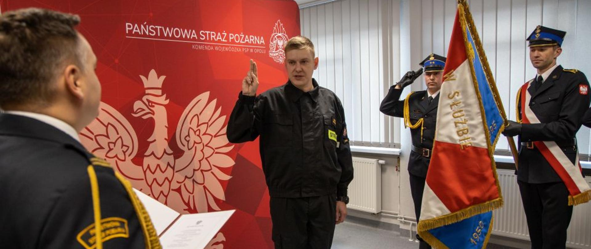 Ślubowanie str. Pawła Szynklera. Strażacy Państwowej Straży Pożarnej w ubraniach galowych i wyjściowych, poczet sztandarowy oraz strażak składający przysięgę (w ubraniu koszarowym) na świetlicy Ośrodka Szkolenia KW PSP w Opolu.
W ślubowaniu wzięli również udział: Zastępca Opolskiego Komendanta Wojewódzkiego PSP w Opolu st. bryg. Arkadiusz Kuśmierski, Zastępca Opolskiego Komendanta Wojewódzkiego PSP w Opolu st. bryg. Wojciech Nawara, pracownik cywilny i funkcjonariusze wydziału technicznego wraz z naczelnikiem bryg. Ryszardem Sałkiem.