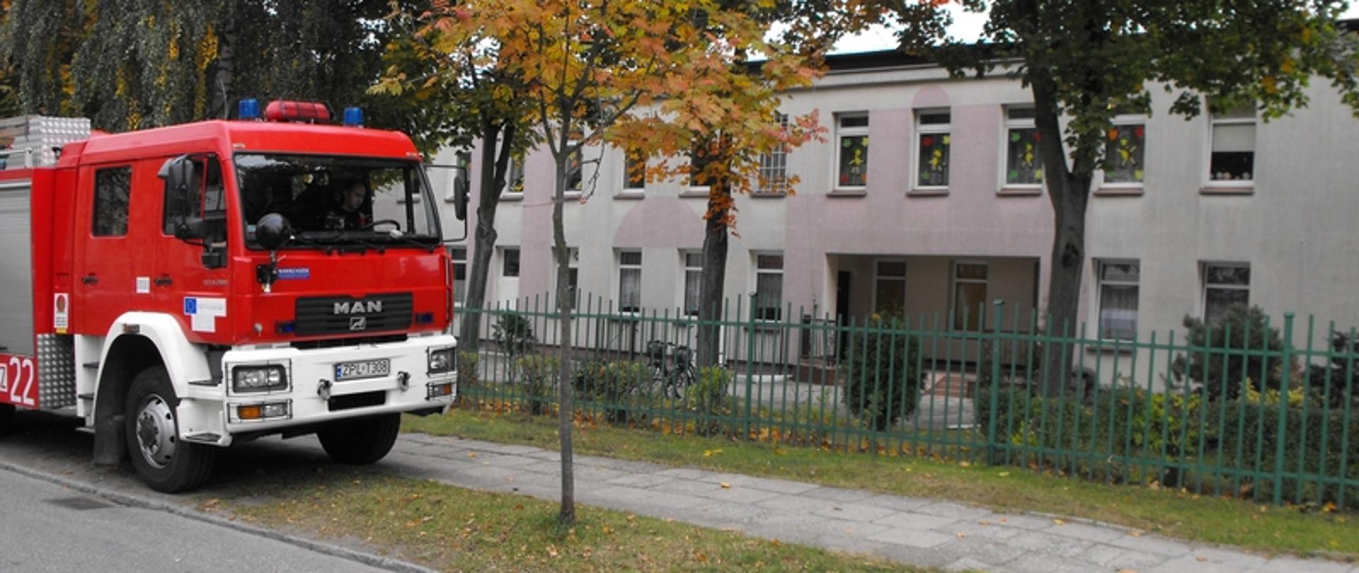 Zdjęcie przedstawia samochód pożarniczy przed żłobkiem