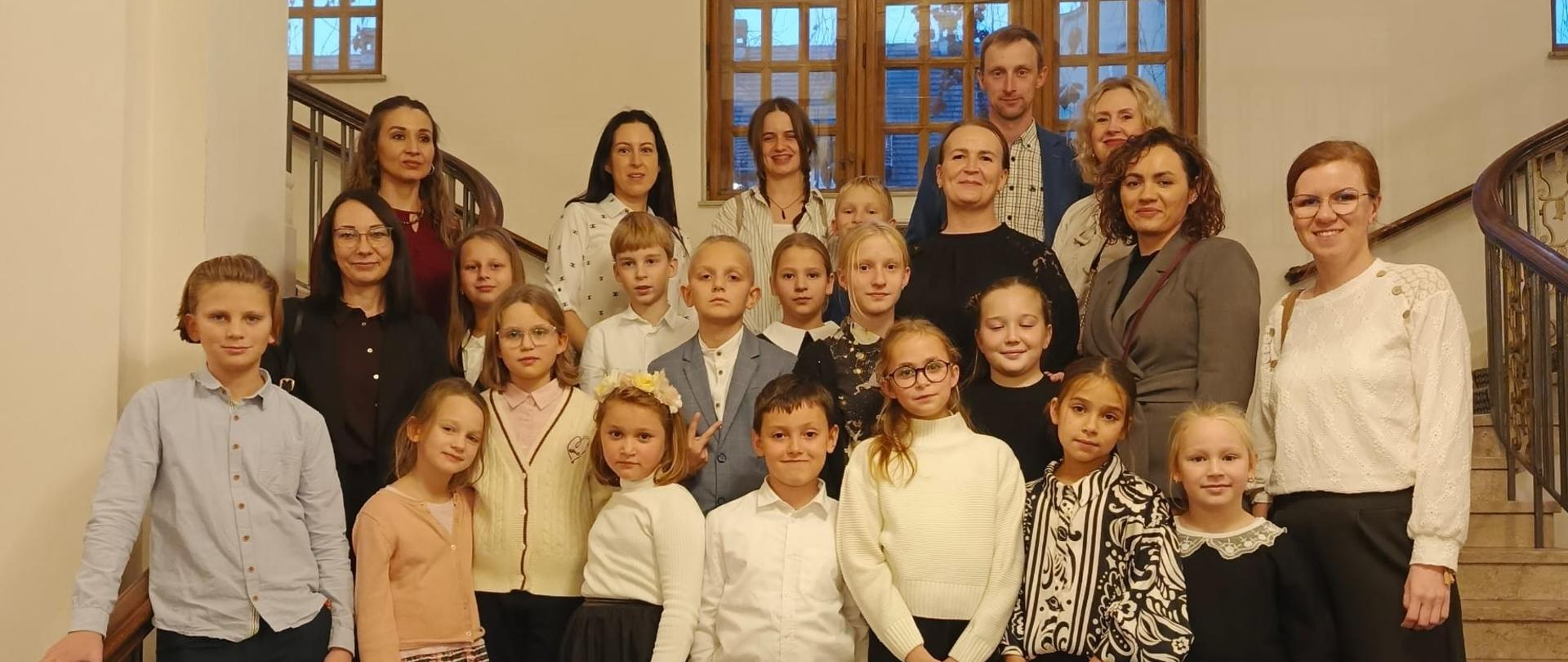 Grupa uczestników wyjazdu na schodach budynku Uniwersytetu Adama Mickiewicza w Poznaniu.