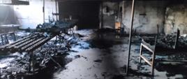 Zdjęcie przedstawia pomieszczenie w zakładzie produkcji mebli po pożarze. Całe pomieszczenie oraz wyposażenie uległo spaleniu.