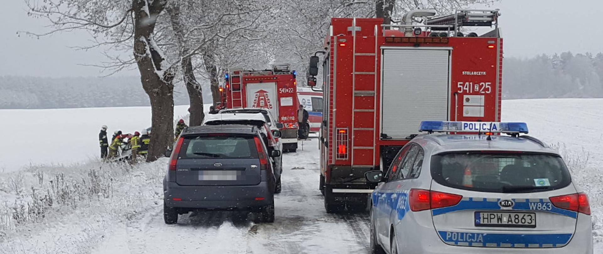 Wypadek samochodu osobowego - samochody ratowniczo-gaśnicze oraz Policji stoją na jezdni