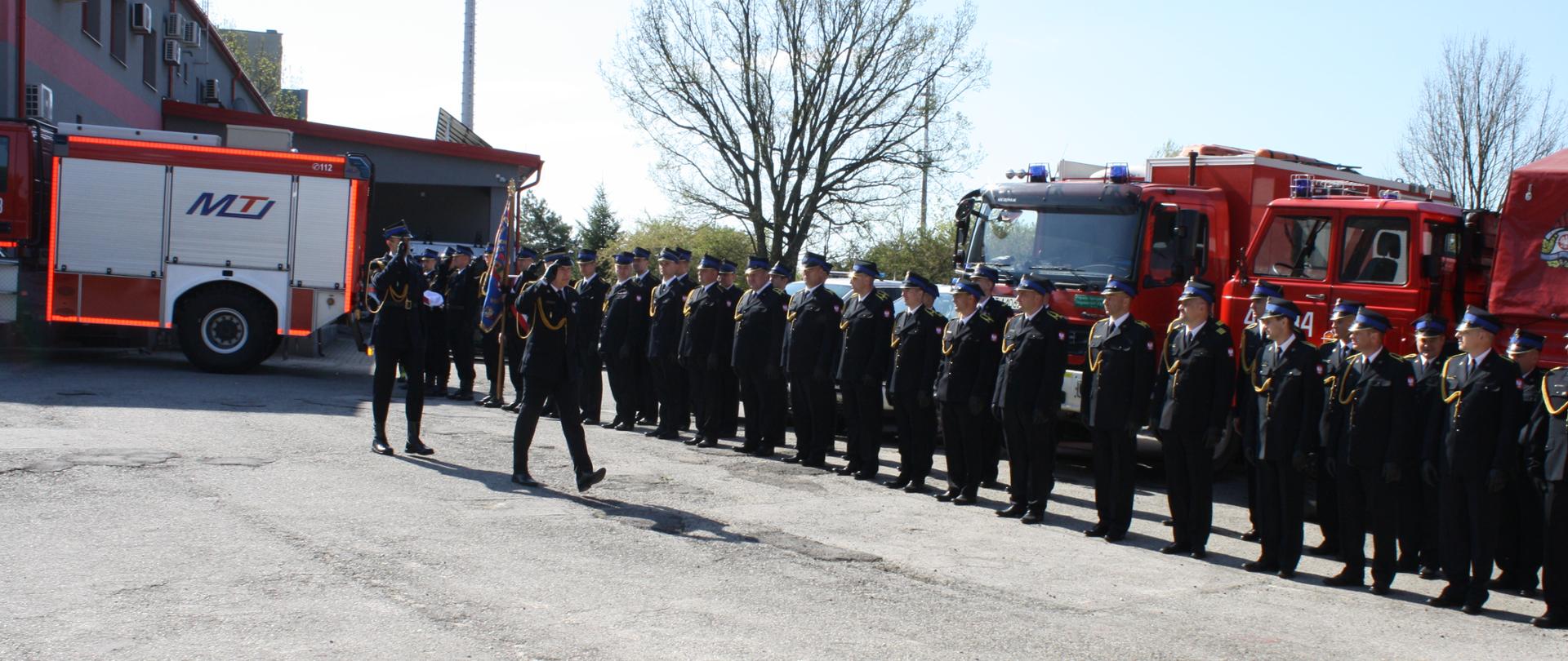 Przegląd pododdziałów przez Komendanta w tle pojazdy pożarnicze