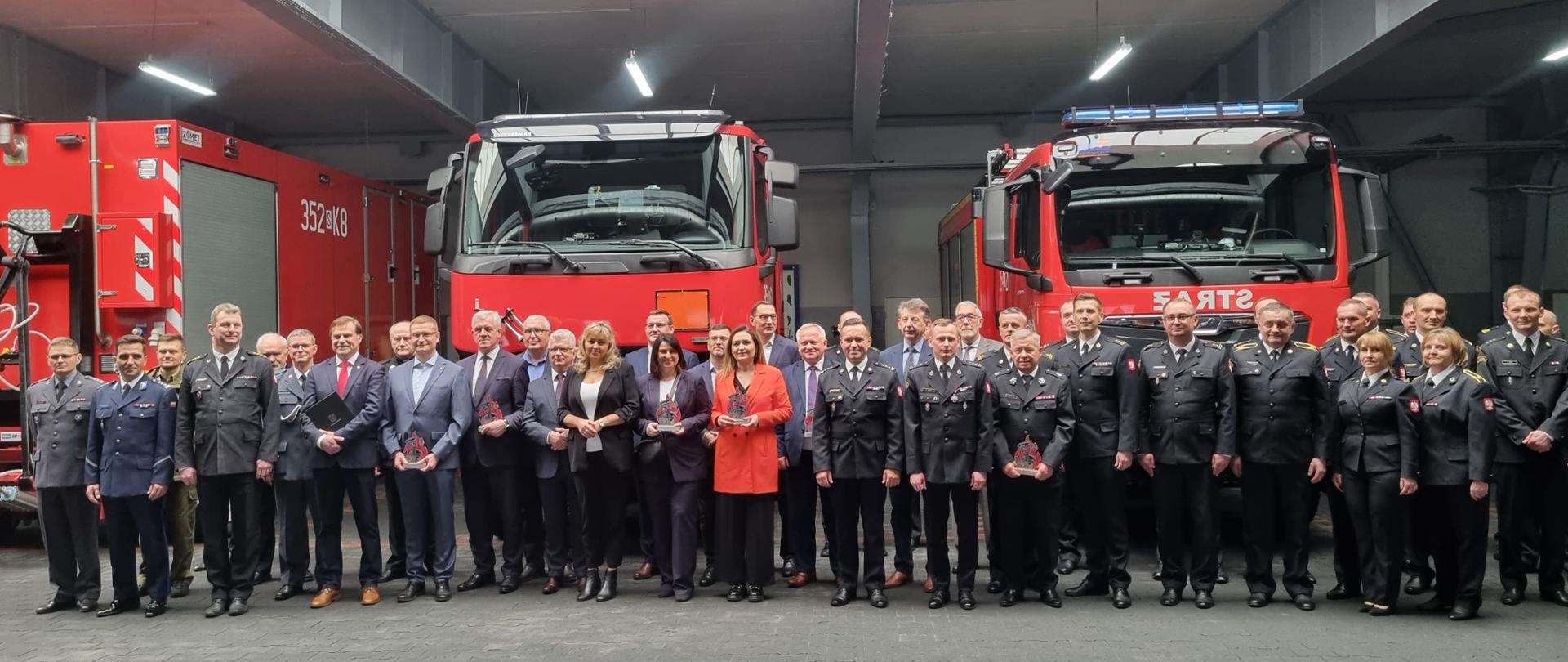 Zdjęcie grupowe uczestników konferencji w tle przekazywany sprzęt.