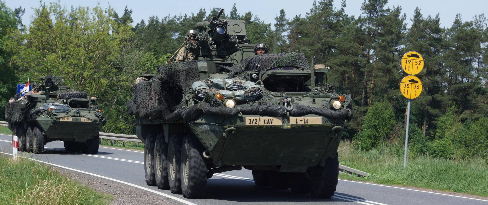 Przejazd kolumny wojskowej. Widoczne wozy bojowe w tle las.