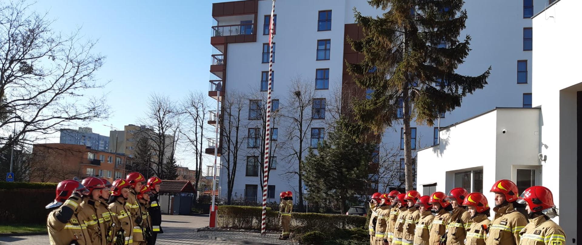 Uroczyste podniesienie flagi państwowej na JRG 5 Gdańsk przez strażaków w ubraniach bojowych na zmianie służby