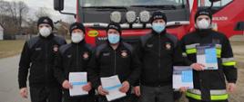 Zdjęcie przedstawia strażaków, którzy zajmują sie dystrybucją ulotek w ramach akcji informacyjnej na temat sczepień przeciwko COVID-19