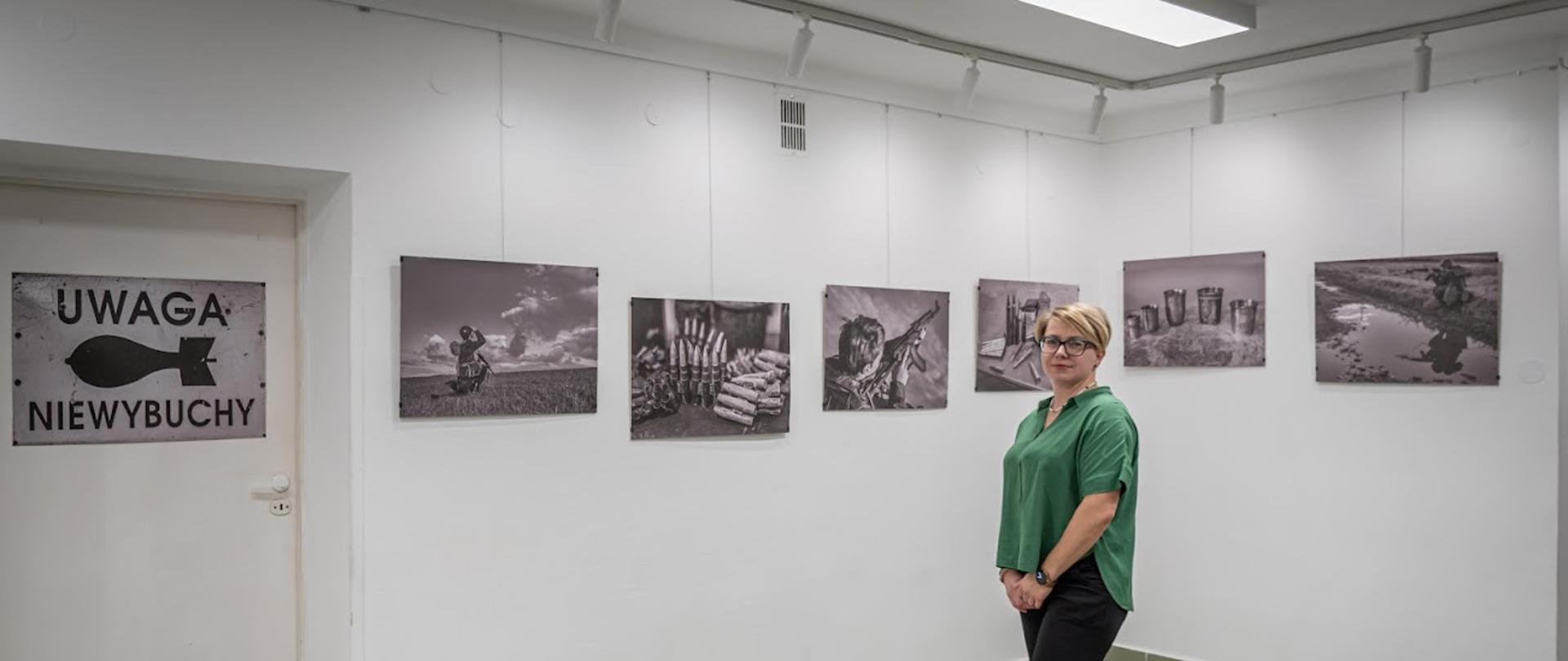 Zdjęcie przedstawia słuchaczkę stojącą na tle swojej wystawy.