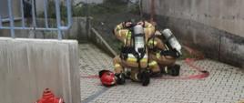 Zdjęcie przedstawia strażaków podczas ćwiczeń znajdujących się przed budynkiem, w którym powstał pozorowany pożar w maszynowni stacji gondolowej. 