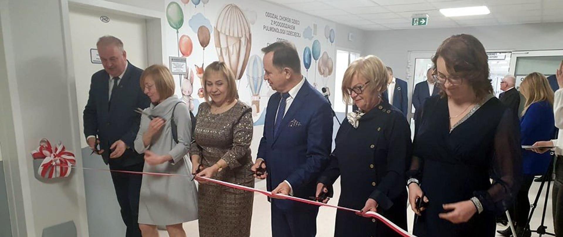 Uczestnicy uroczystości w szpitalu przecinają wstęgę