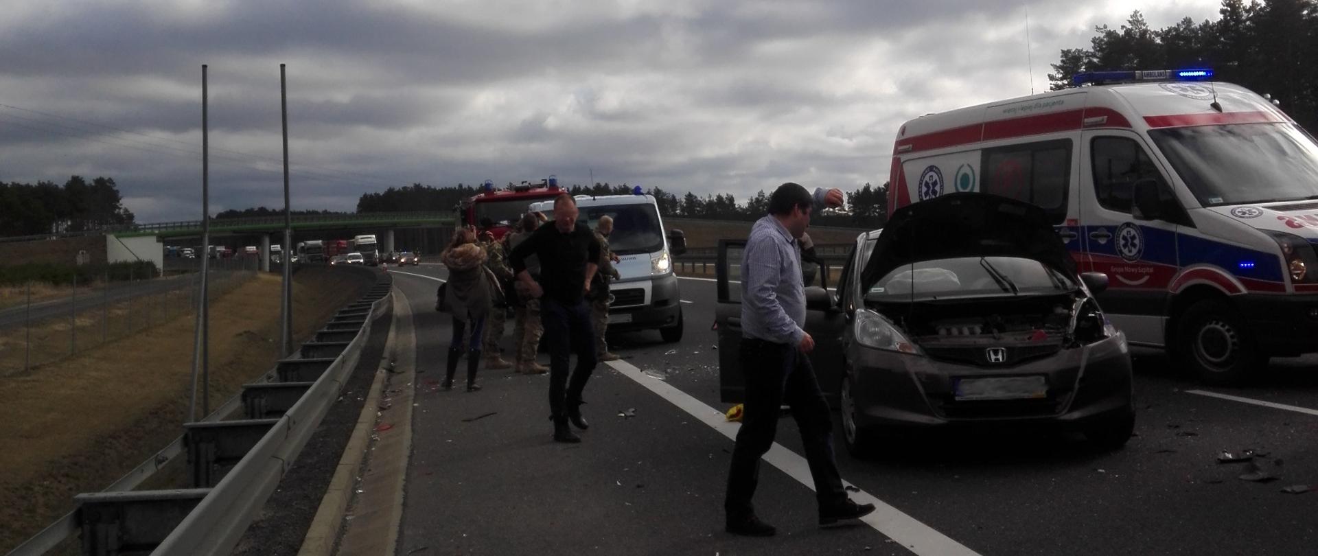 Zdjęcie przedstawia samochodowy wypadek na drodze a w powietrzu odlatujący helikopter Lotniczego Pogotowia Ratunkwego