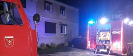 TRAGICZNY POŻAR MIESZKANIA. Na zdjęciu widać samochodu strażackie stojące przed budynkiem.