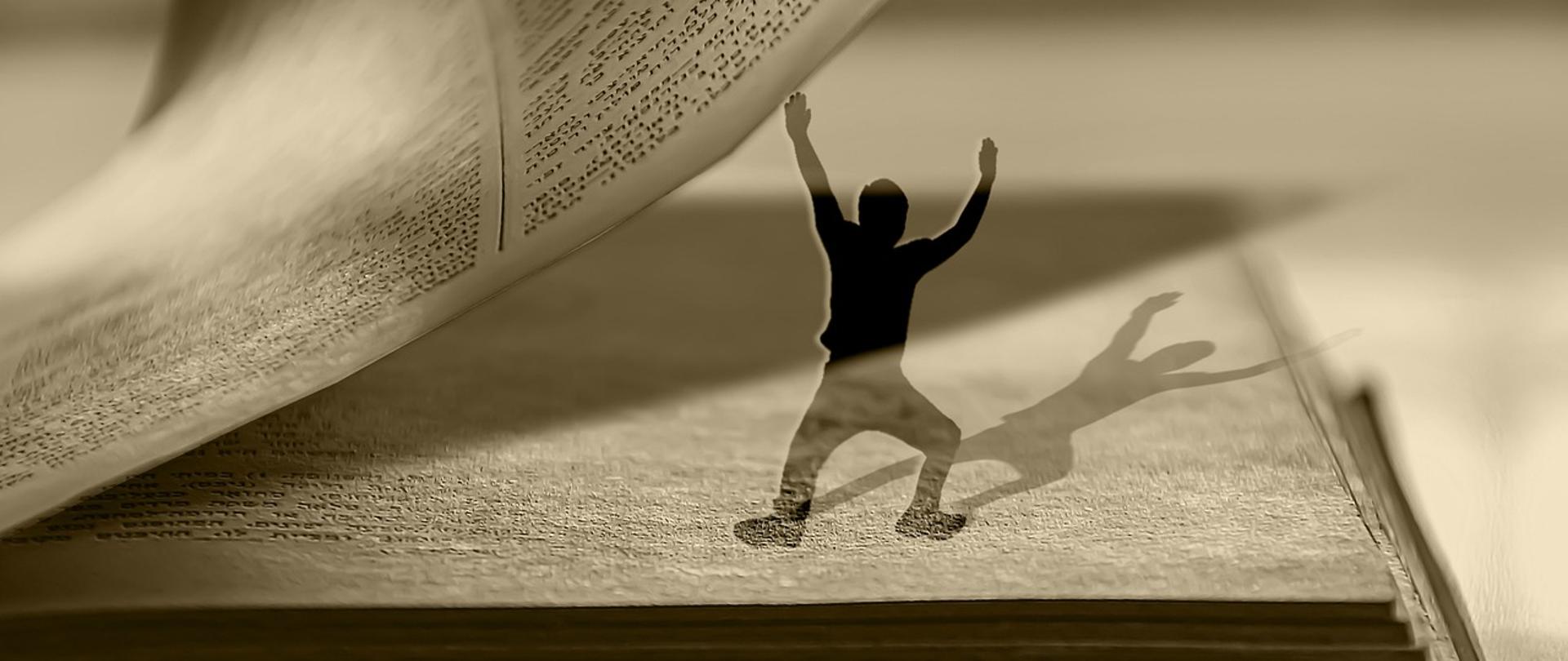 Na zdjęciu mężczyzna podtrzymujący kartki w książce.