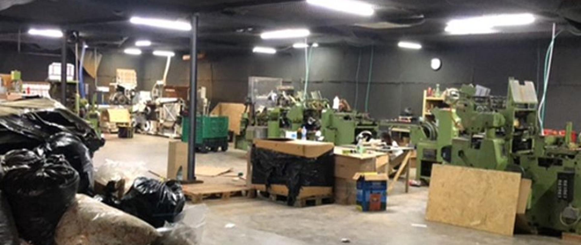 Hala, w której stoją maszyny do produkcji wyrobów tytoniowych, worki z surowcami.