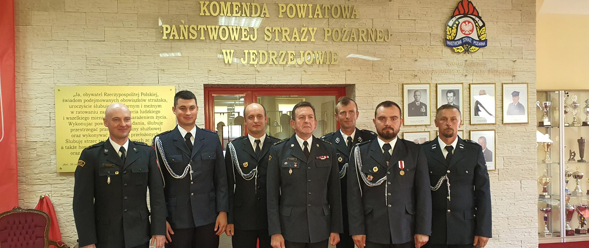 Strażacy na tle ściany pozują do zdjęcia