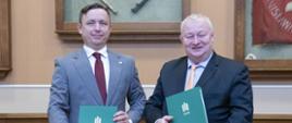 Prezes PAA Andrzej Głowacki oraz prof. dr. hab. inż. Rafał Wiśniowski, Prorektor ds. Współpracy AGH stoją obok siebie trzymając w rękach podpisane porozumienie o współpracy