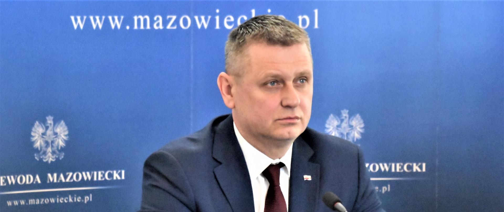 Wicewojewoda siedzący przy stole, w tle granatowa ścianka z logo Wojewody.