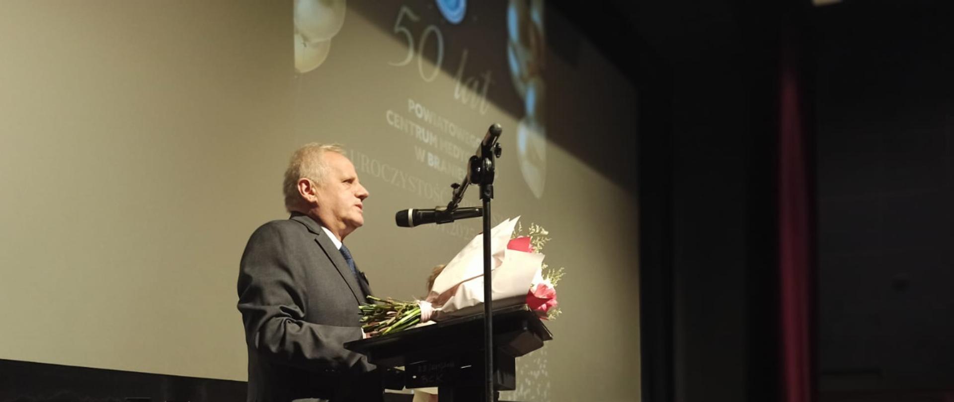 Mężczyzna stoi na scenie przed mikrofonem 