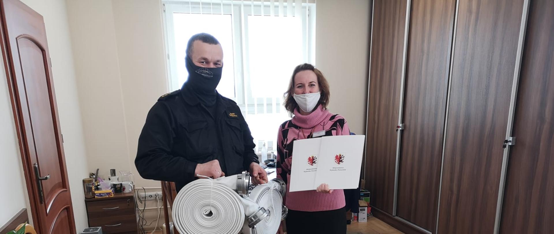 kapitan Adam Gwizdała Dowódca Jednostki Ratowniczo Gaśniczej w Świeciu przekazuję wąż pożarniczy wójtowi gminy Lniano panii Joannie Tomaszewskiej z Urzędu Gminy w Pruszczu