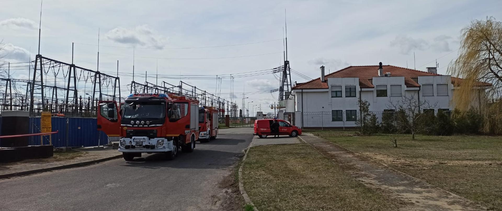 Wozy strażackie na tle stacji elektroenergetycznej.