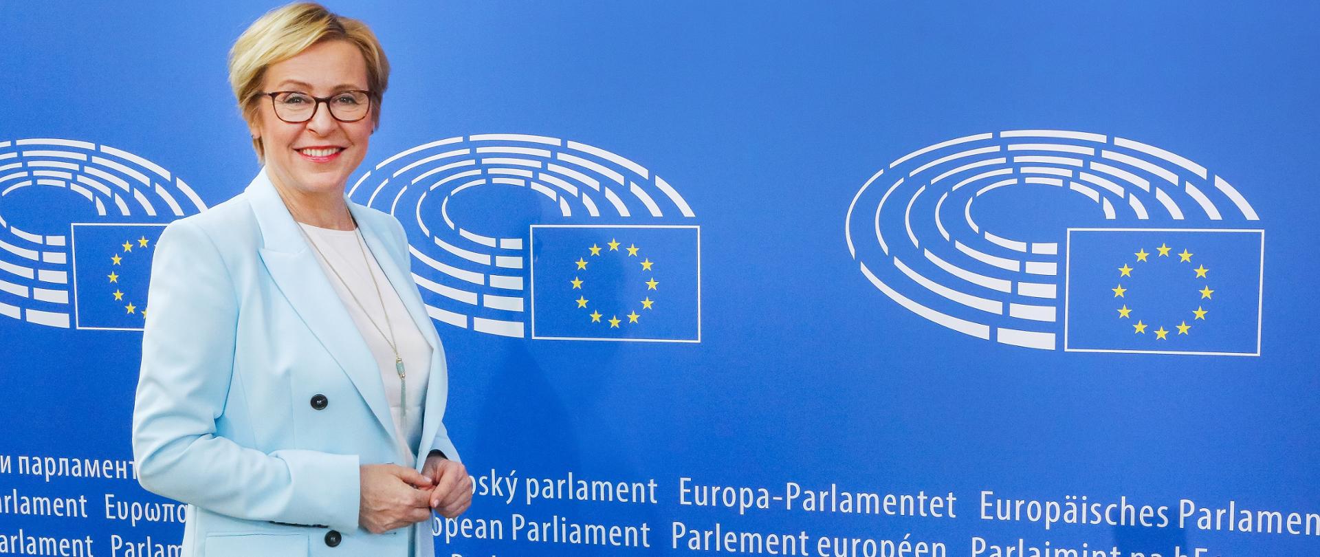 Europosłanka Jadwiga Wiśniewska na tle baneru Parlamentu Europejskiego
