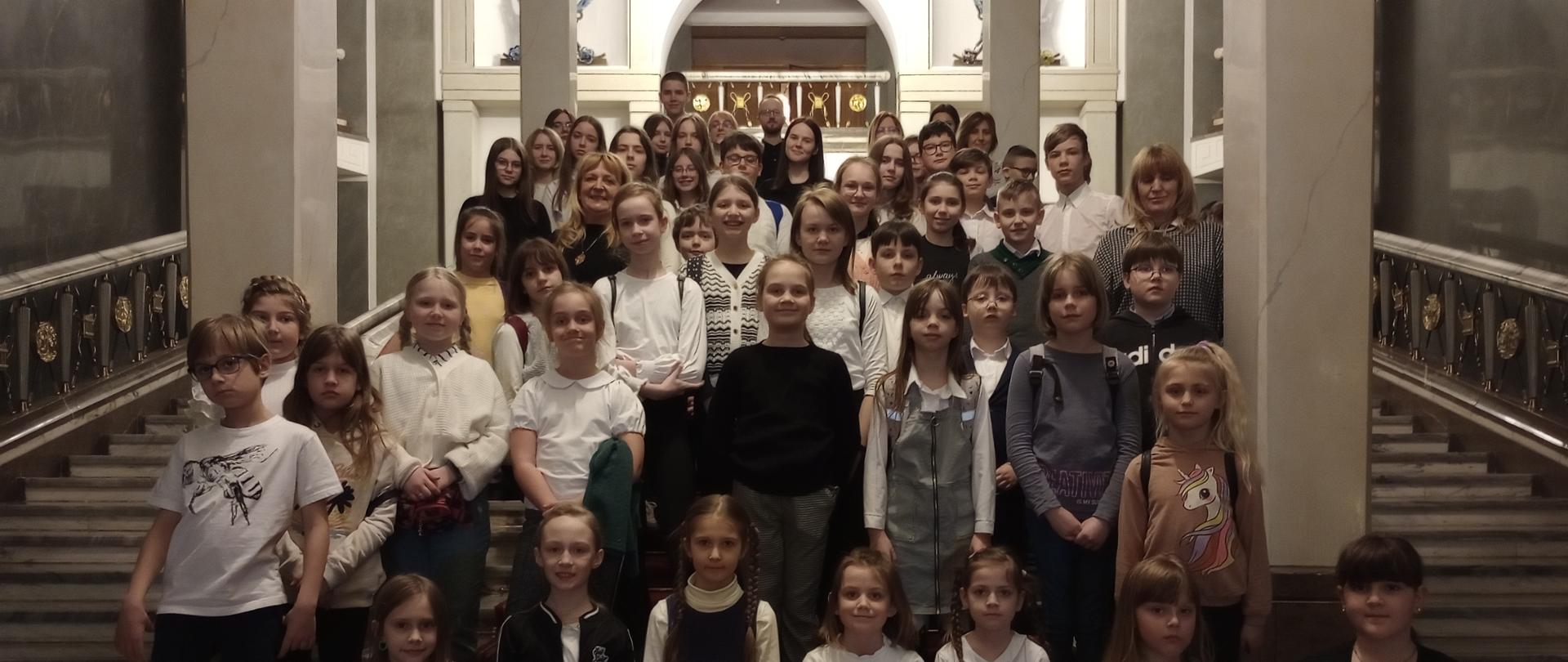 Zbiorowe zdjęcie wycieczkowiczów na schodach w Teatrze Wielkim w Warszawie