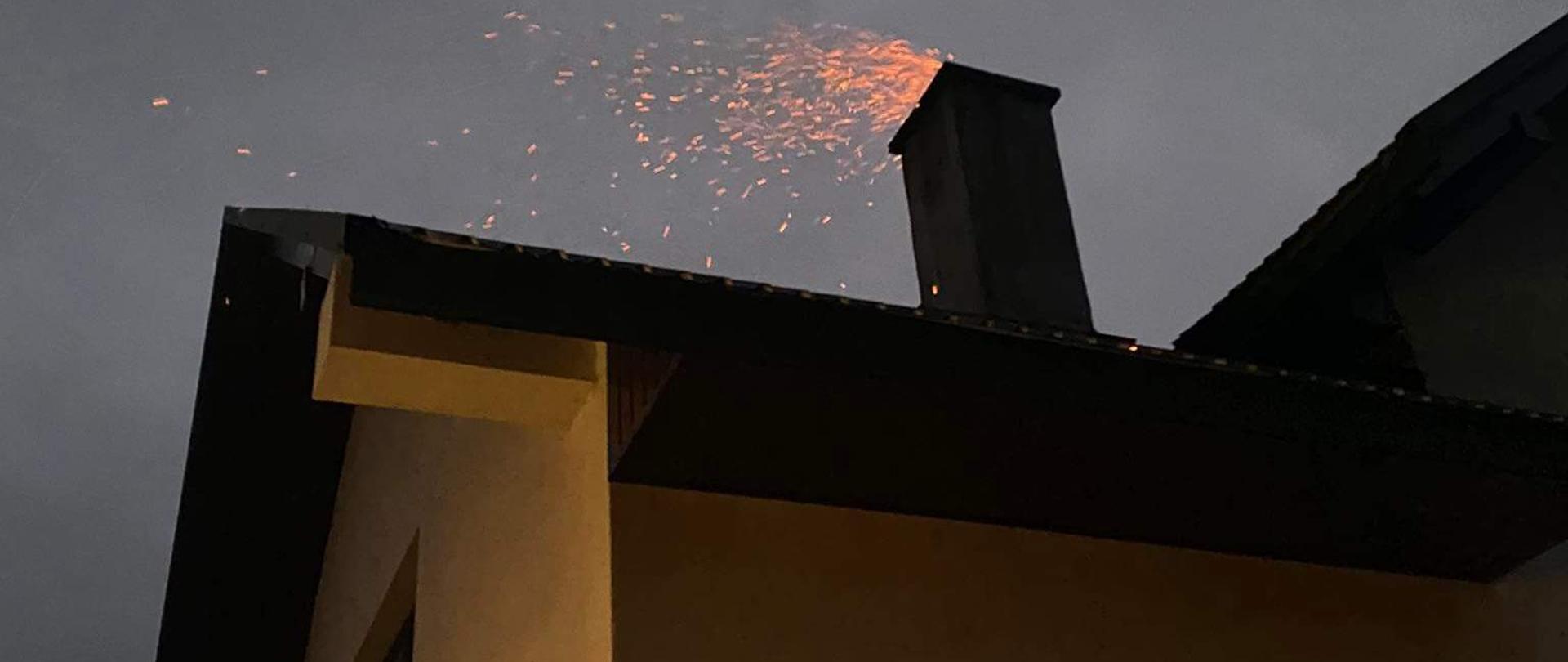 Zdjęcie przedstawia budynek jednorodzinny z przewodem kominowych z którego wydobywa się ogień w związku z pożarem sadzy.