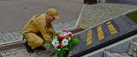 Strażak Państwowej Straży Pożarnej składa wieniec pod pomnikiem "W hołdzie pomorskim strażakom". 