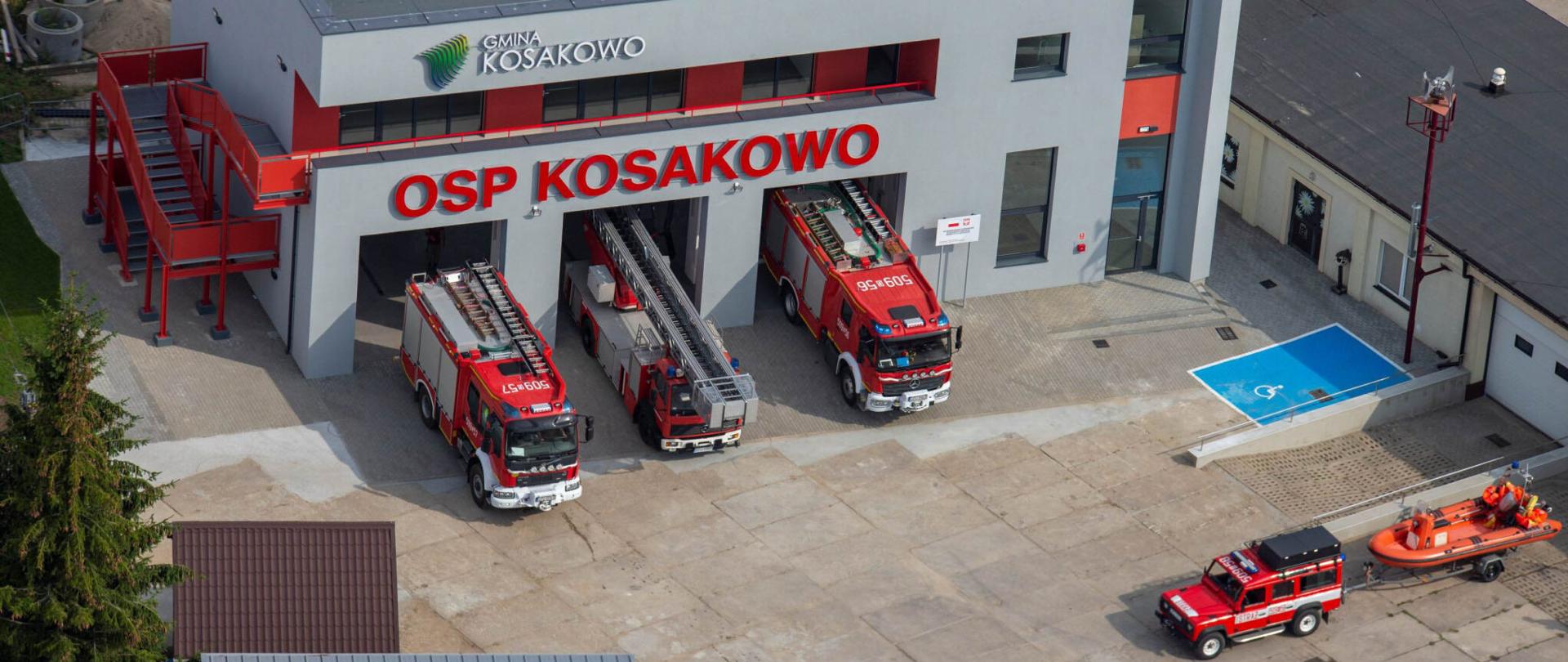 Trzy samochody ratowniczo gaśnicze stoją przed bramami remizy Ochotniczej Straży Pożarnej w Kosakowie.