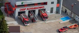Trzy samochody ratowniczo gaśnicze stoją przed bramami remizy Ochotniczej Straży Pożarnej w Kosakowie.