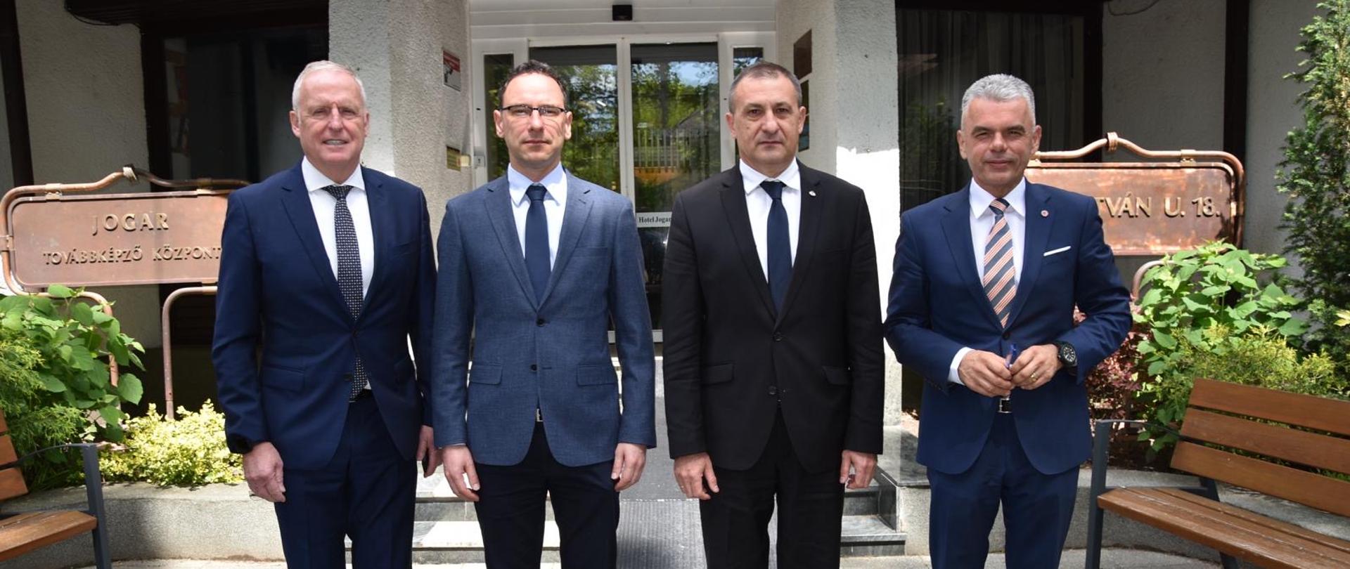 Mężczyźni pozujący do zdjęcia. stoją przed budynkiem w garniturach.